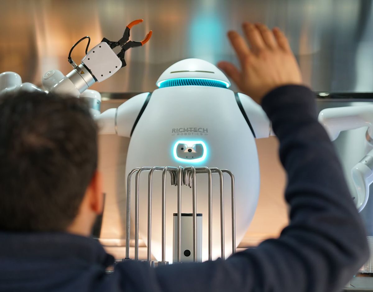 Richtech ADAM robot with two arms and grippers serving a customer at a bar